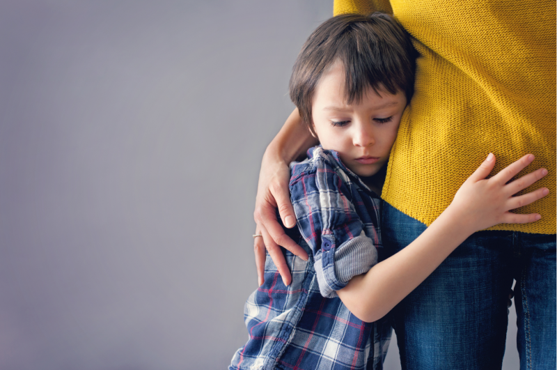 niño triste abrazándose a su madre