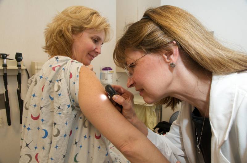 Un médico examina los lunares a una paciente. Imagen por Chistriana Care