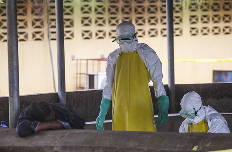 Trabajadores de salud liberianos se preparan para recoger el cuerpo de una víctima del ébola del área de espera de un hospital en Monrovia. / Efe