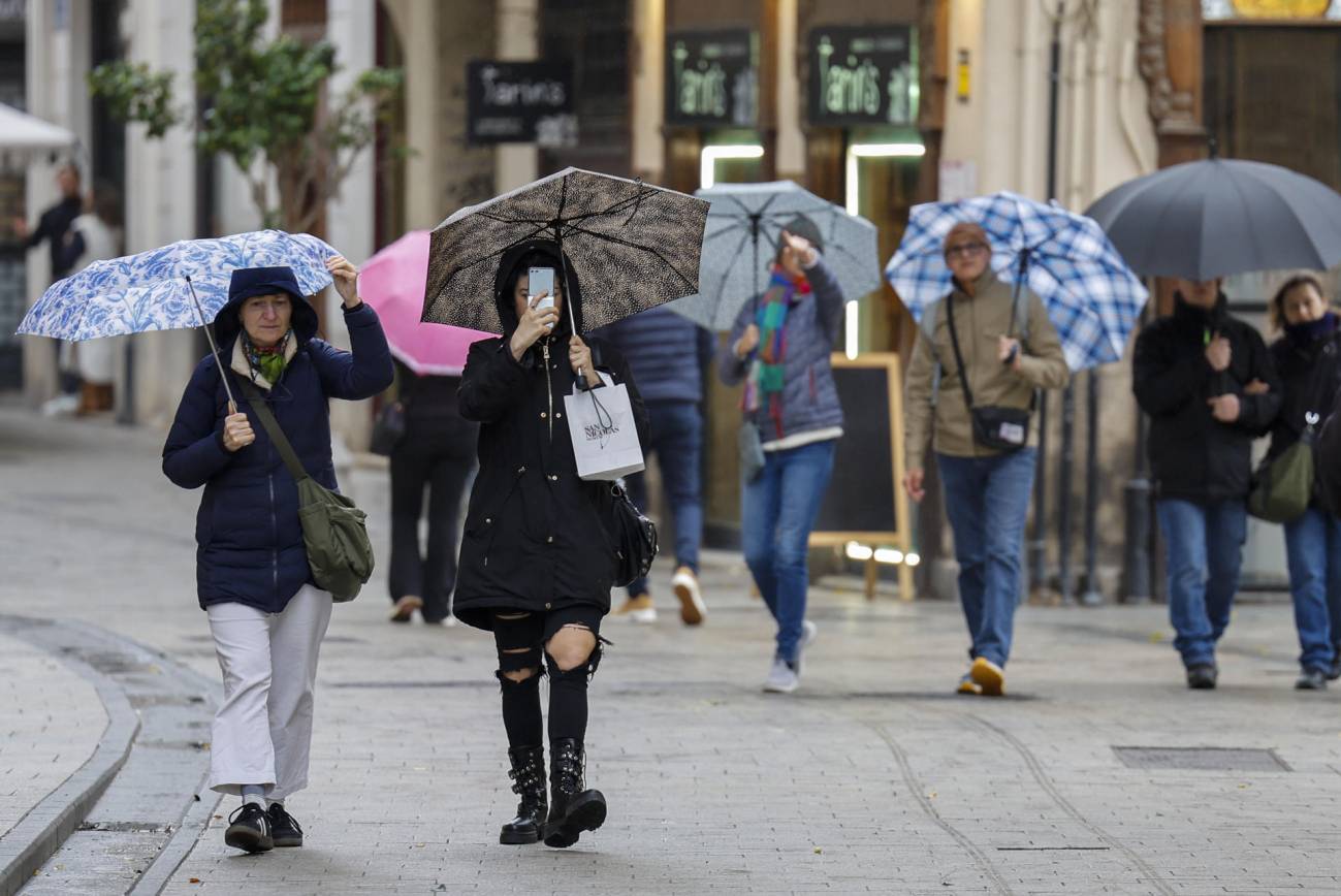 Imágenes de varias personas en la calle bajo la lluvia. 