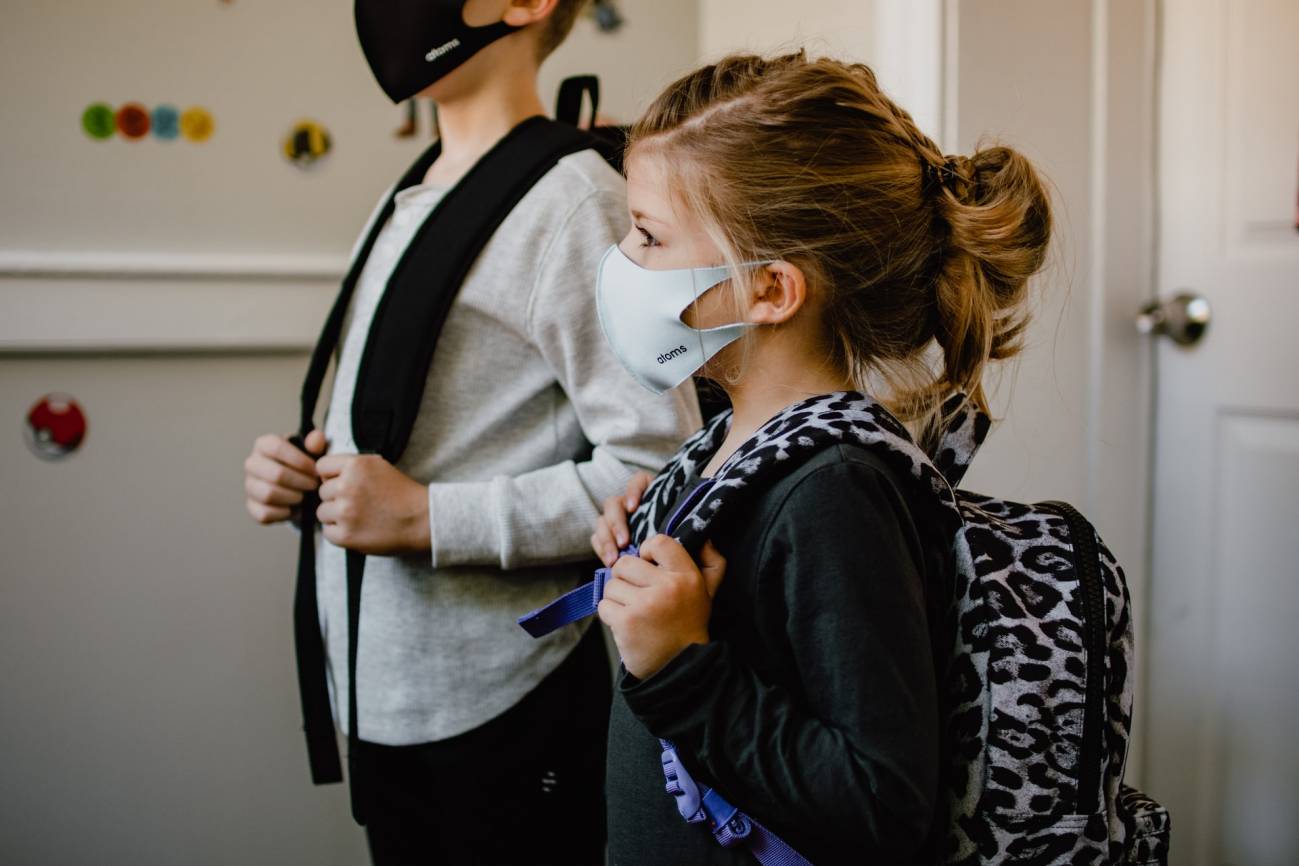 Dos niños con mascarilla preparados para ir al colegio