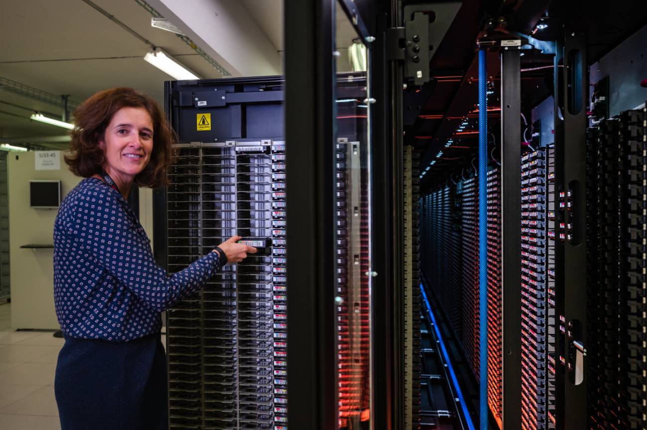 María Alandes en el centro de datos del CERN con uno de los robots de cinta. / Noemí Carabán / CERN