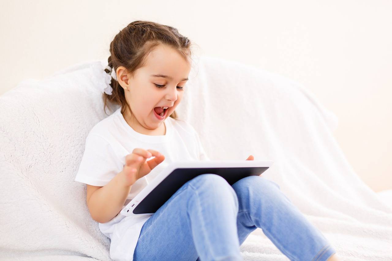 Niña con una tablet sentada en un sofá