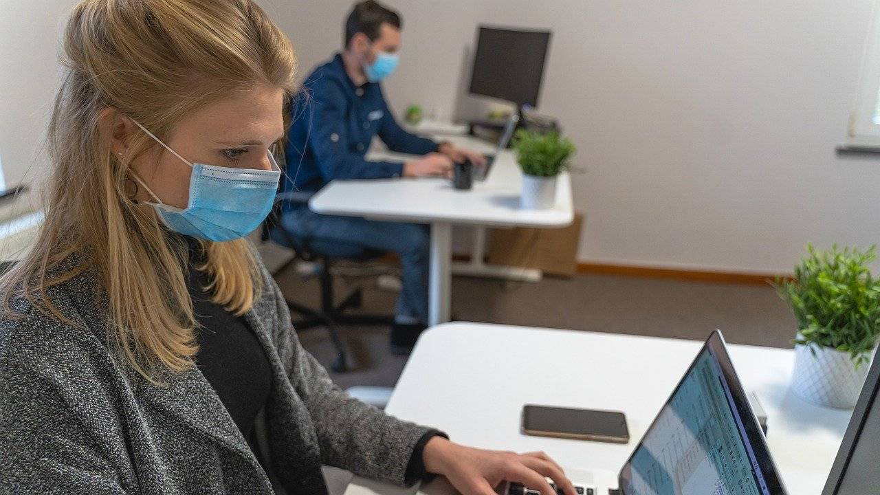 personas trabajando con distancia y mascarilla