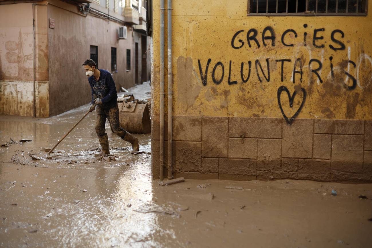 Un voluntario retira fango de una calle de Paiporta (Valencia). / EFE/ Biel Aliño