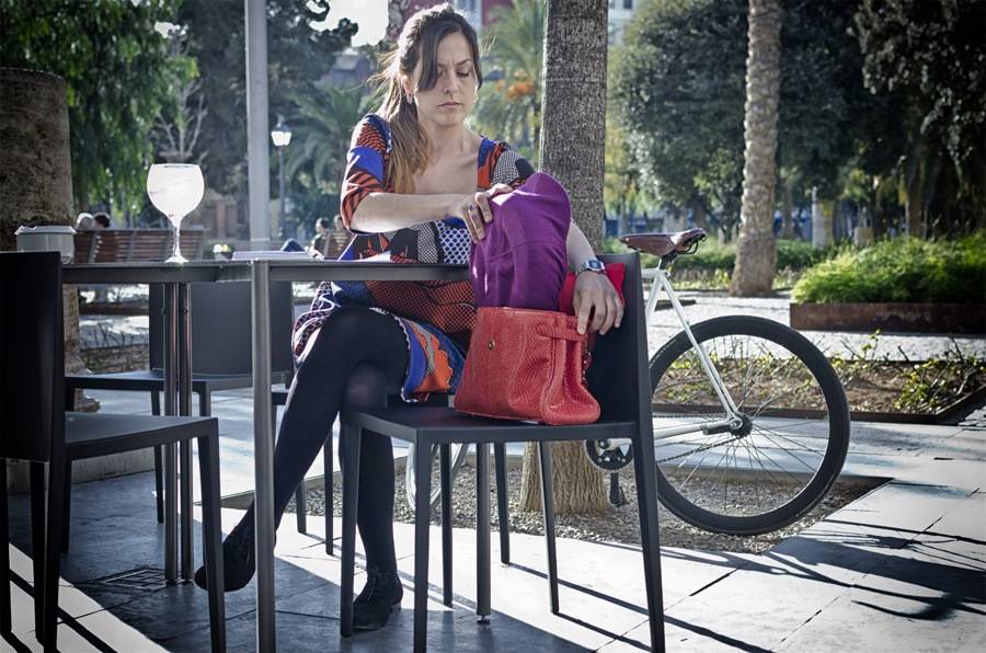 Una mujer guarda el casco plegado en su bolso. 