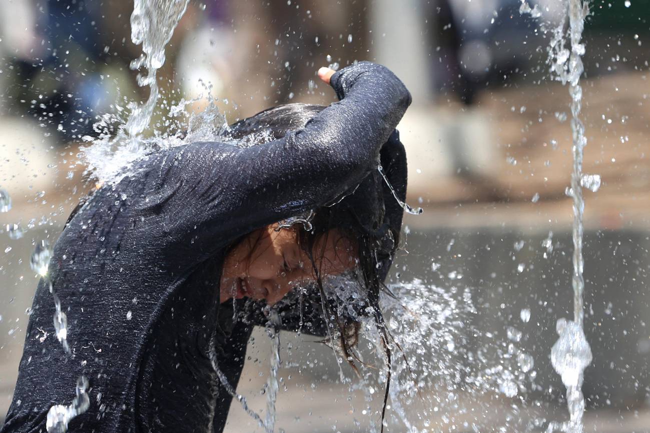 niño que se refresca en una fuente 
