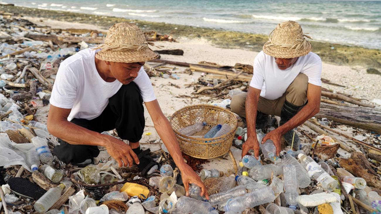Un grupo de personas recoge botellas de plástico en una playa contaminada de Indonesia