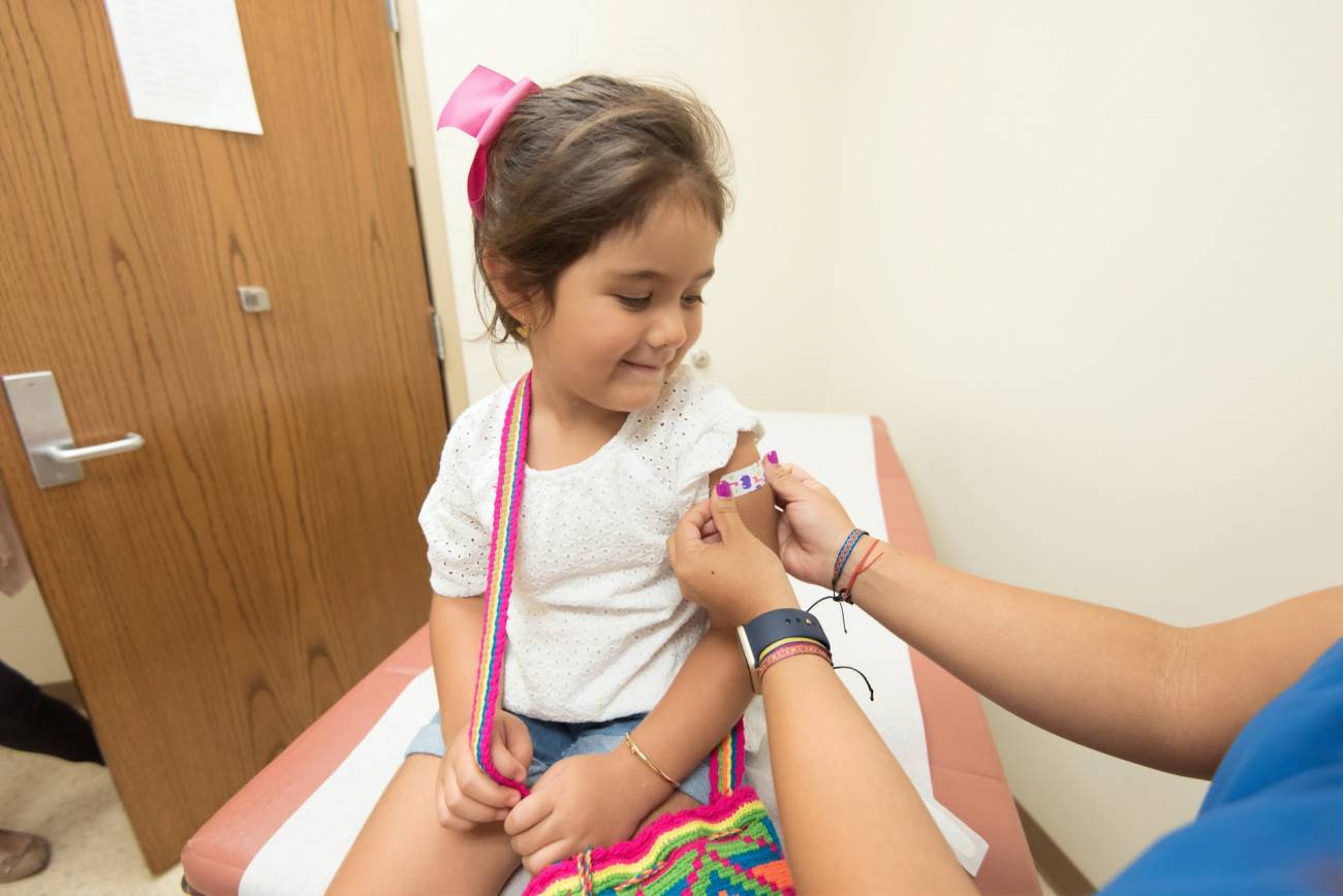 Enfermera pone una vacuna a una niña pequeña