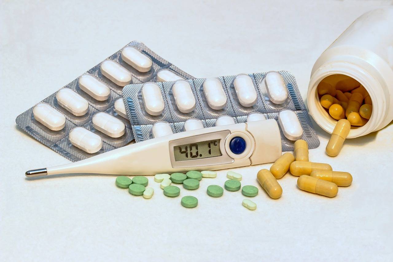 termómetro con 40 grados de fiebre y pastillas