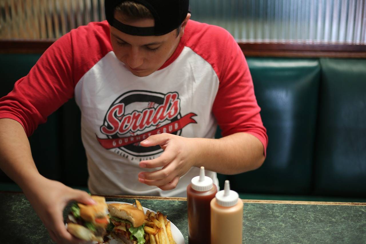 adolescente comiendo una hamburguesa