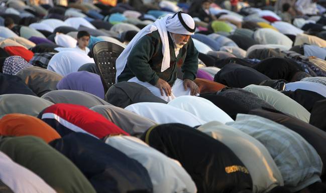 Un palestino se sirve de una silla para poder seguir las oraciones durante el Eid al-Adha en el campo de Al Nusairat, en el centro de la franja de Gaza. / Efe