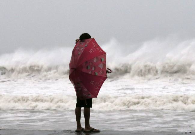 Una mujer se protege del viento del tifón Hagupit en Borongan (Filipinas). / Efe