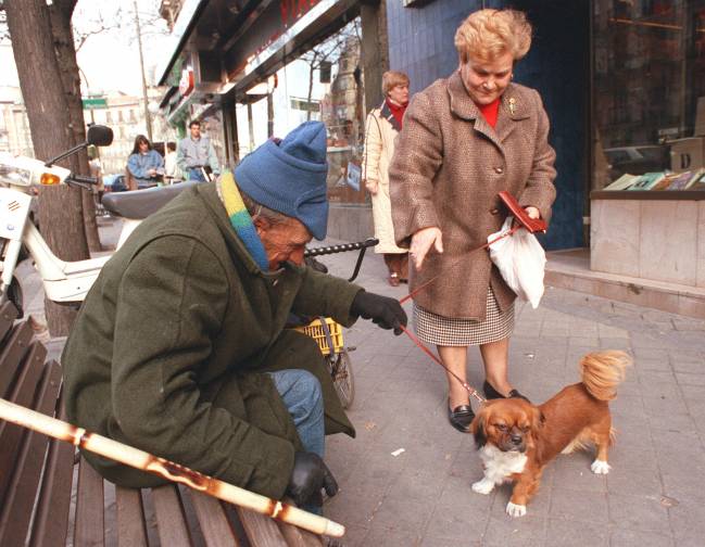 Un mendigo descansa en un banco en una calle de Madrid. / Efe