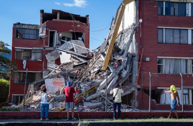 Personas observan viviendas afectadas luego de un terremoto de magnitud 7,4 este lunes, en Pereira (Colombia)