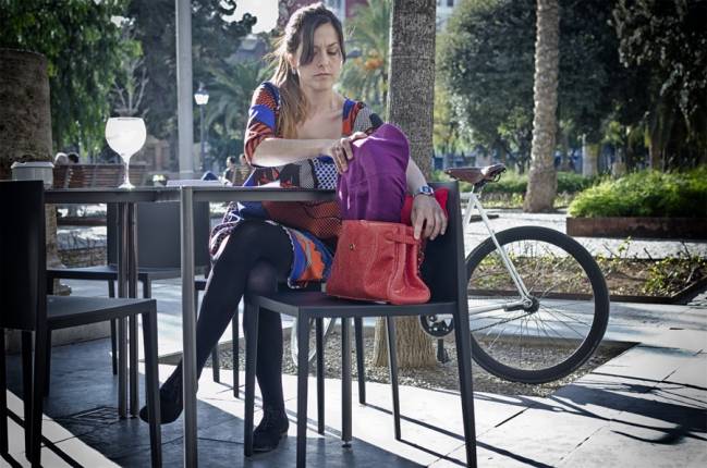 Una mujer guarda el casco plegado en su bolso. 