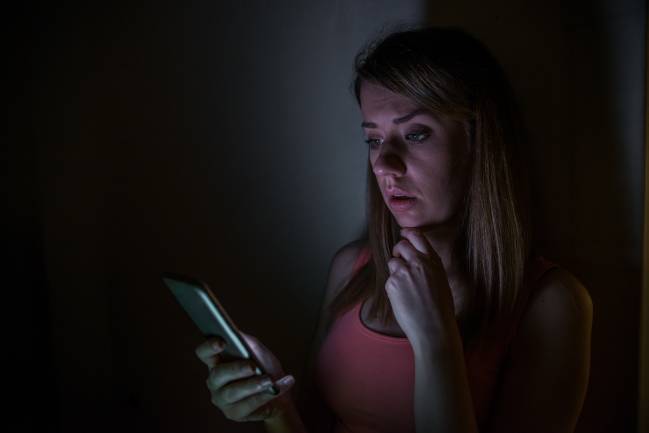 Una persona leyendo el móvil en la oscuridad. 