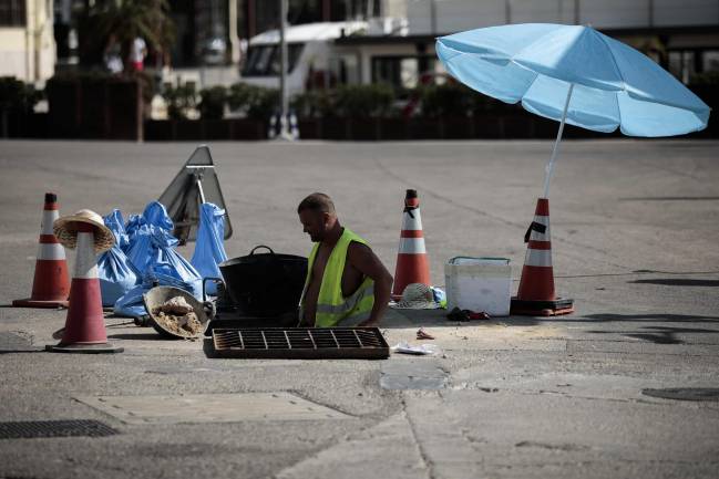 Un trabajador se protege del sol con una sombrilla