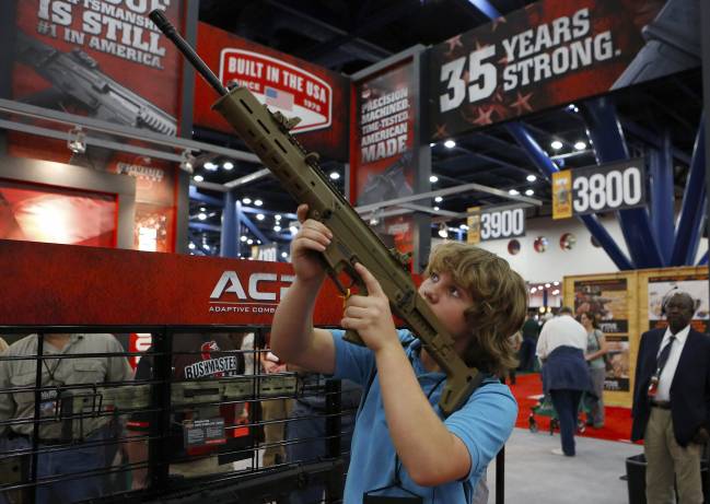 Un niño de 13 años prueba un arma en la convención anual de la Asociación Nacional del Rifle en Houston (EE UU)./ Efe