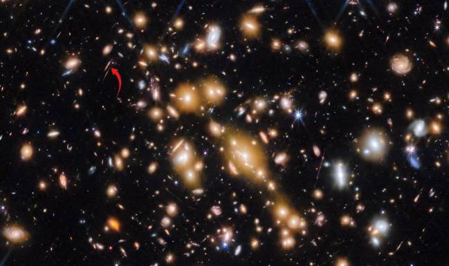 La flecha roja indica el arco de las Gemas Cósmicas donde se han encontrado los más lejanos cúmulos estelares. / ESA/Webb, NASA & CSA, L. Bradley (STScI), A. Adamo (Stockholm University) and the Cosmic Spring collaboration
