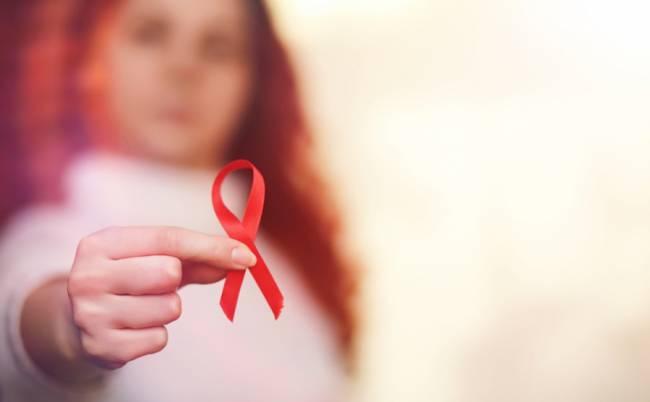 Mujer sosteniendo un lazo rojo