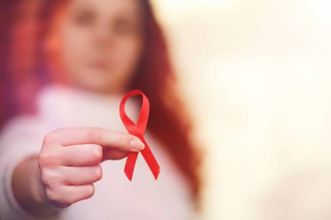 Mujer sosteniendo un lazo rojo