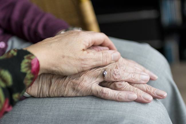 una mano anciana cogida por un sanitario