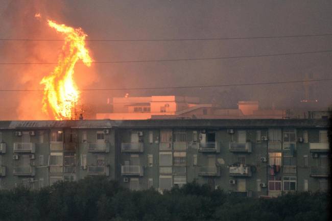 Una columna de fuego se eleva tras un bloque de viviendas