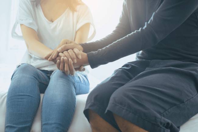 dos personas sentadas sosteniendo las dos las manos juntas