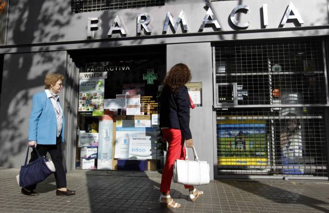 Una mujer contempla la fachada de una farmacia, en una imagen de archivo. / EFE