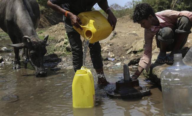 Dos hombres rellenan garrafas con agua potable procedente de una tubería rota en Bombay (India)