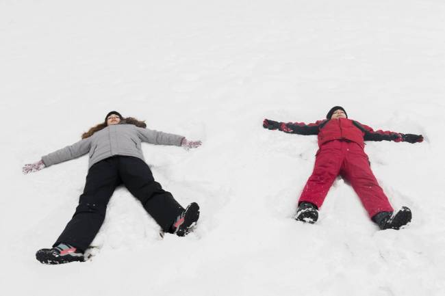 Dos niños haciendo ángeles de nieve