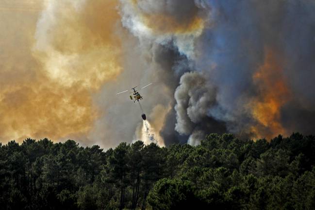 Un helicóptero lanza agua sobre un incendio forestal en Seizures, cerca a Penalva do Castelo (Portugal)