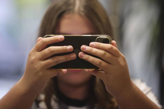 Fotografía de archivo de una chica consultando su teléfono móvil