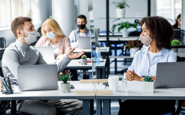 personas trabajando en una oficina con mascarilla