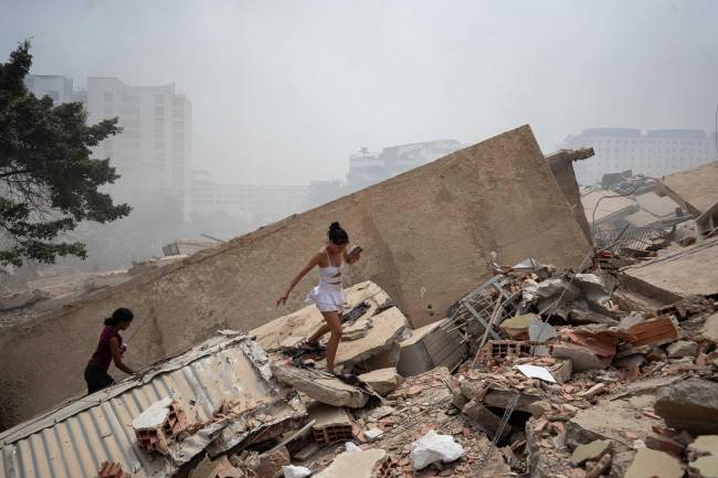 Personas caminan entre los escombros de edificios afectados por los terremotos en La Guaira (Venezuela)