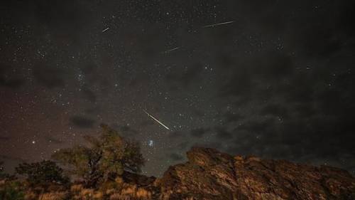 Lluvia de meteoros Perseidas atraviesan un cielo en 2024. A la izquierda, el resplandor rosáceo de la aurora. La galaxia de Andrómeda aparece en la parte superior, justo a la izquierda del centro. NASA/Preston Dyches, CC BY
