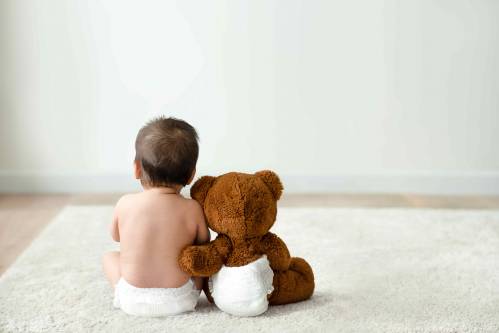 bebe con un oso de peluche de espaldas