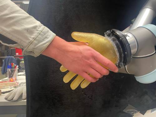 Mano humana estrecha mano de un robot con piel artificial que tiene tacto