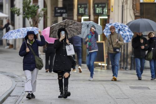 Imágenes de varias personas en la calle bajo la lluvia. 