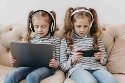 Dos gemelas usando dispositivos móviles