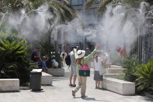 En la imagen de archivo varios turistas tratan de mitigar el calor bajo una nube de agua vaporizada