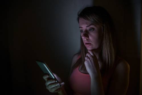 Una persona leyendo el móvil en la oscuridad. 