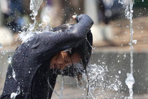 niño que se refresca en una fuente 