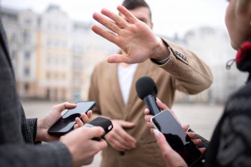 Persoa entrevistada se tapa la cara ente los medios