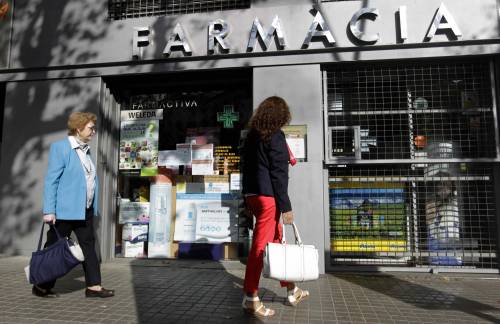 Una mujer contempla la fachada de una farmacia, en una imagen de archivo. / EFE