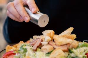 mujer echando sal a la comida